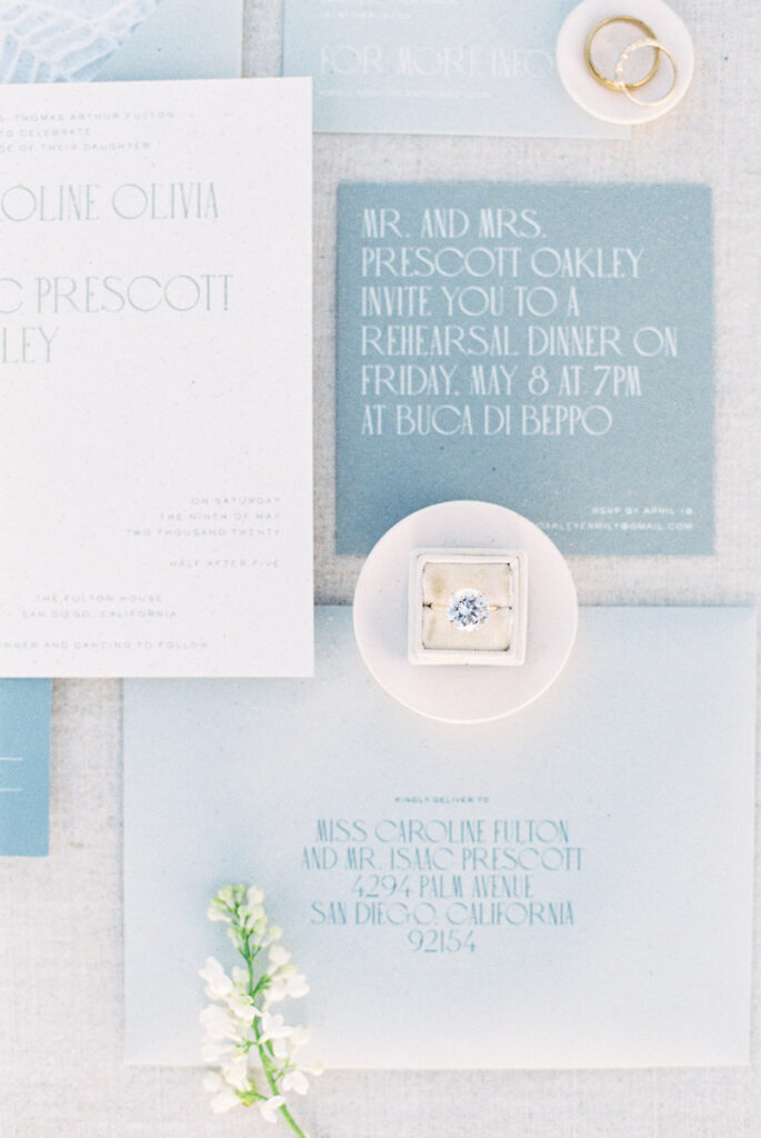 pale blue wedding invitations, ring in white ring box, white florals with invites