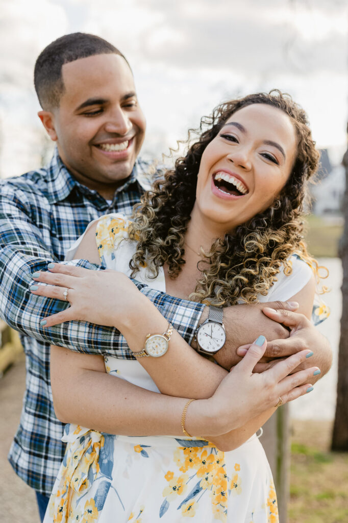 Man and women laughing and holding on to each other in park. Spring Lake New Jersey for engagement session photos by Simone Jaramillo Photography