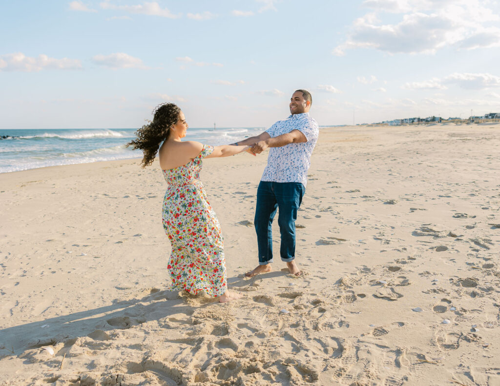Man and women play on beach during engagement session in Spring Lake Beach, New Jersey. Photo taken by Simone Jaramillo Photography