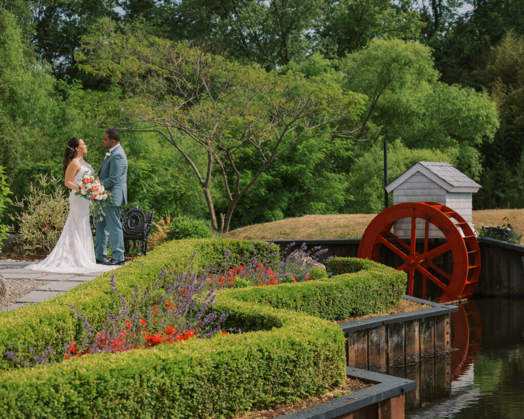 The Mill at Lakeside Manor couple portrait with the mill wheel and garden walkway