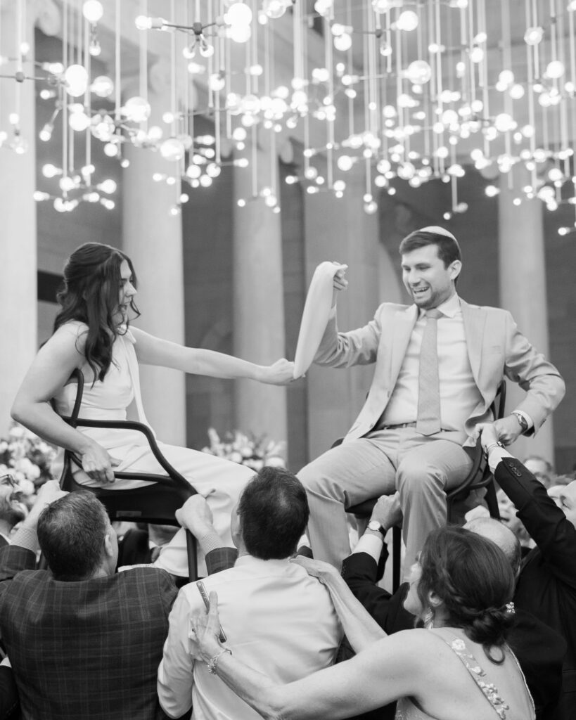 bride and groom in the middle of a hora dance