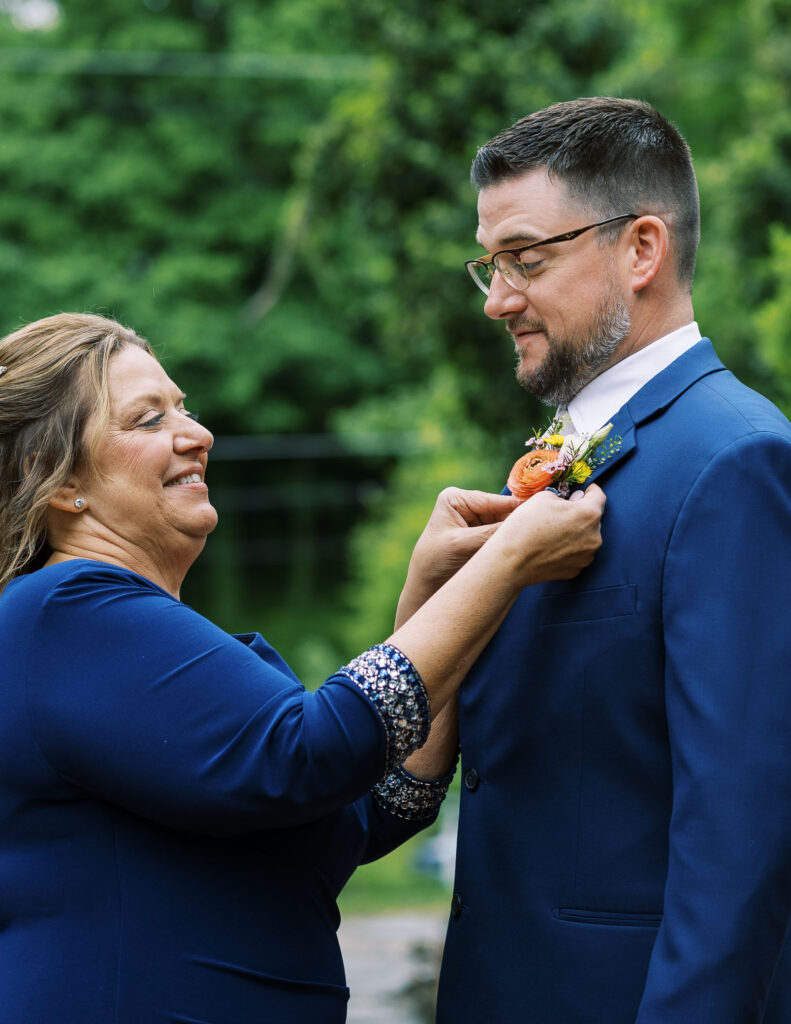 Grooms wedding boutonniere being pinned by mom