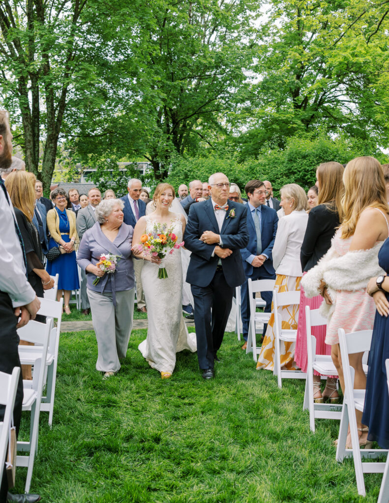 Bride walking down the aisle with parents to get married