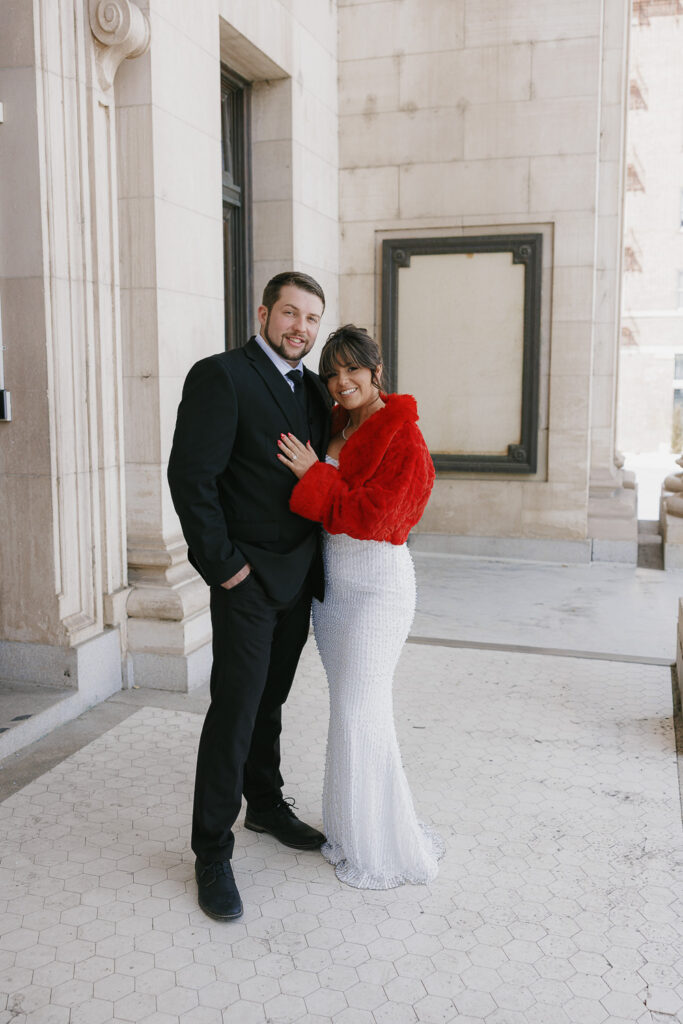 Man in black suit and women in white long gown and red cropped jacket, Downtown Reno Nevada,  Engagement photos with Simone Jaramillo Photography